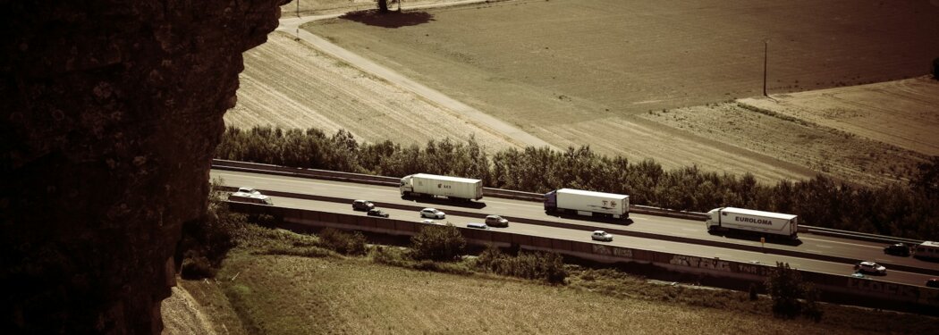 trail photography of running vehicles on street between grass field